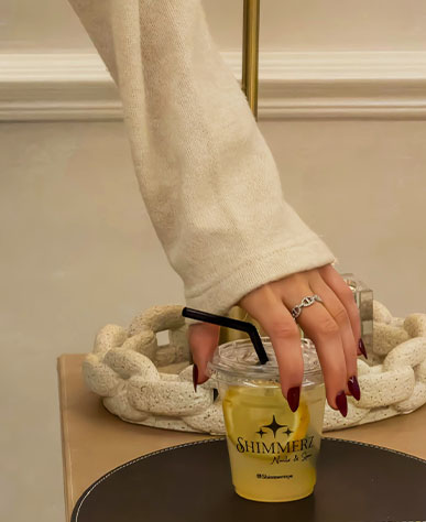 Client's freshly manicured hand reaching for a Shimmerz branded drink